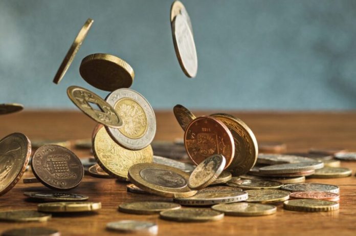 monedas-de-plata-y-oro-y-monedas-que-caen-sobre-madera-828x548